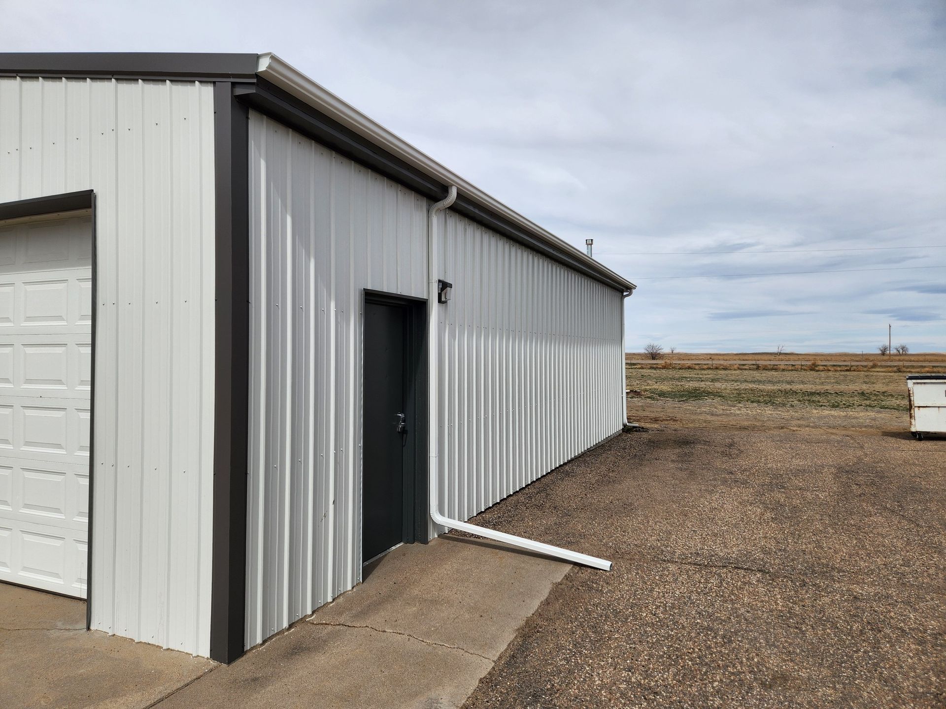 A white building with a black door and a garage door