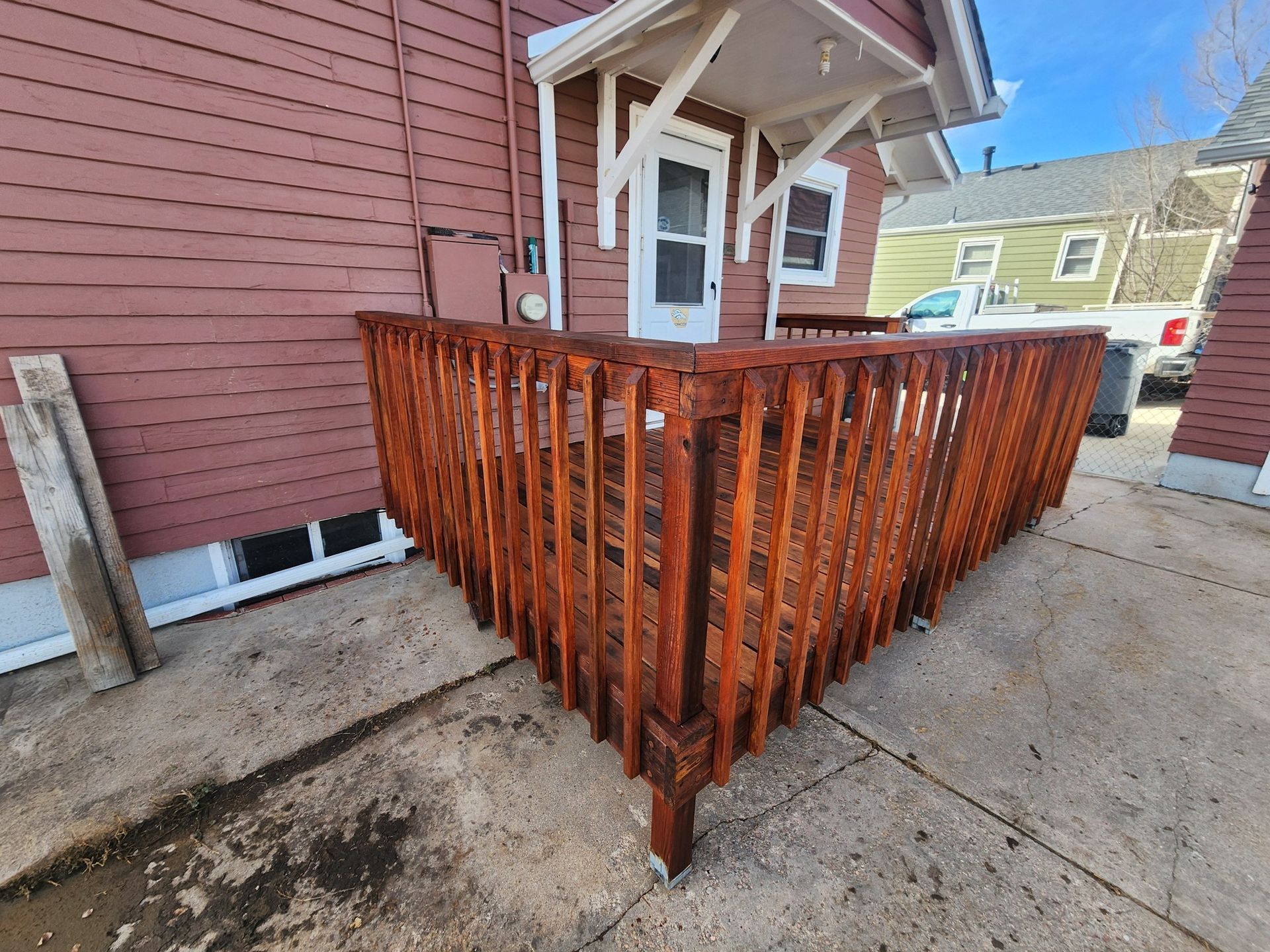A wooden deck is sitting in front of a red house.