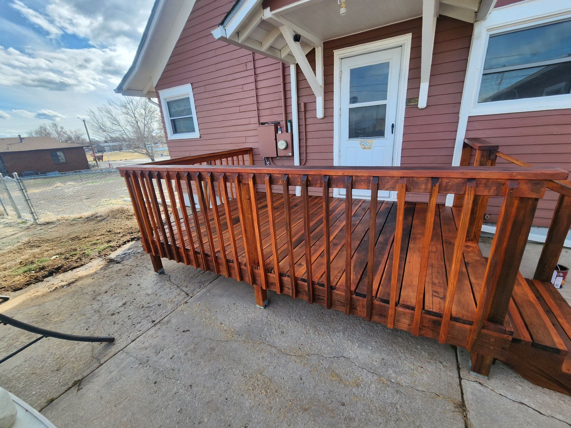 A wooden deck is sitting in front of a house.