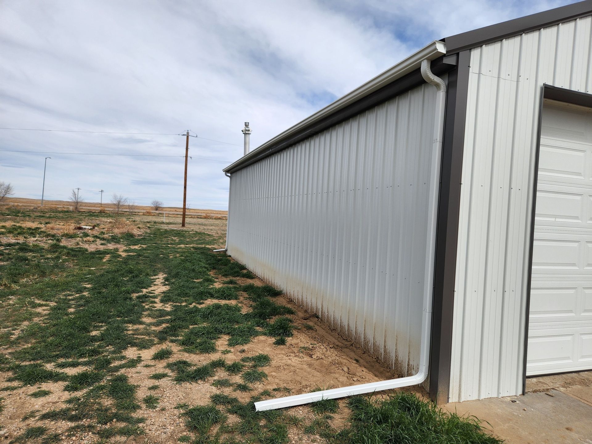 A white garage with a gutter on the side of it.