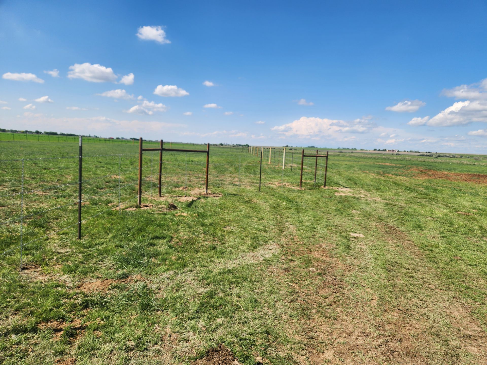 A grassy field with a fence in the middle of it