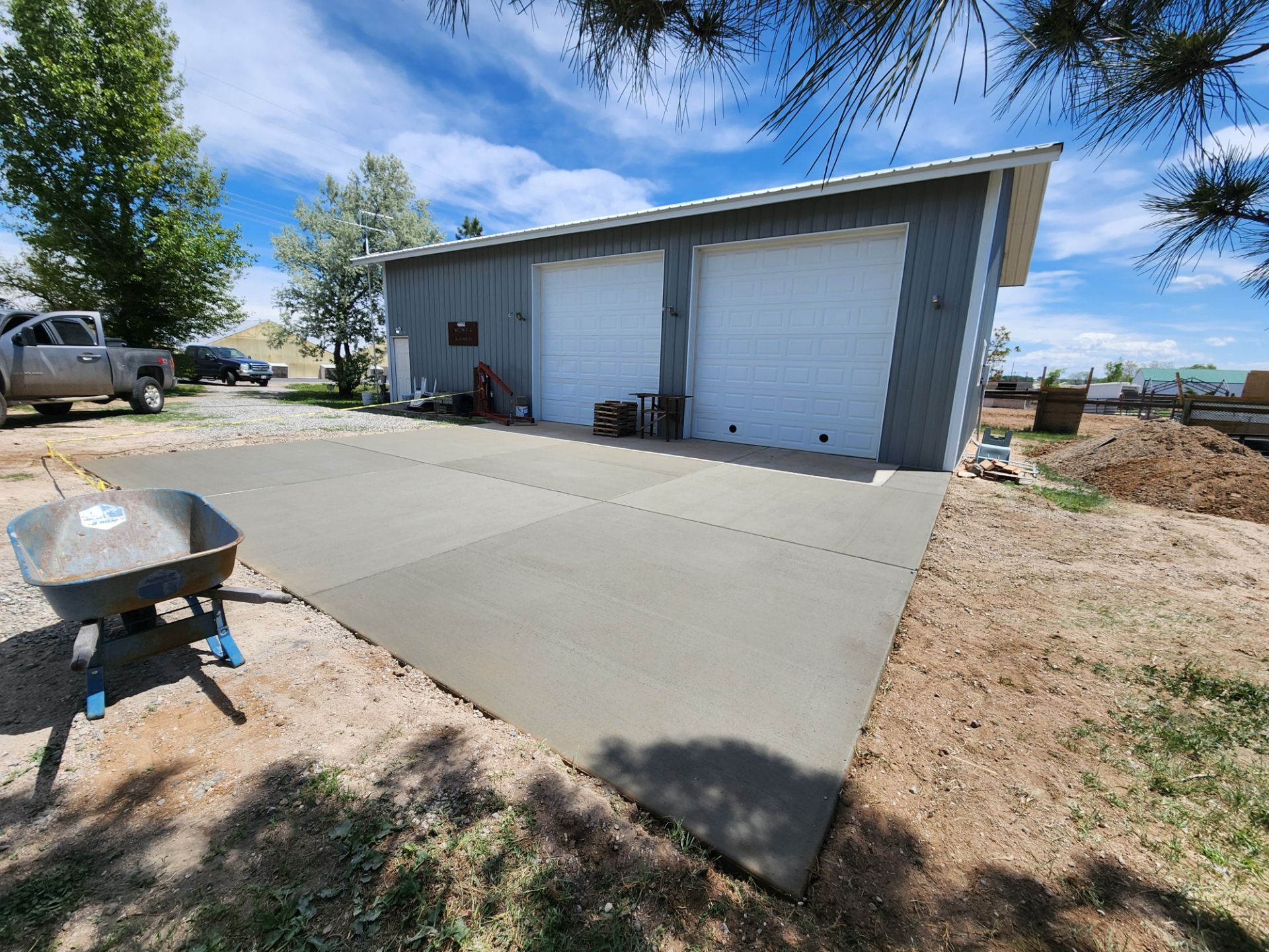 There is a wheelbarrow in front of a garage.