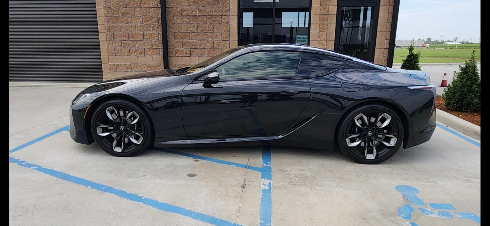 A black sports car is parked in a handicapped parking spot.