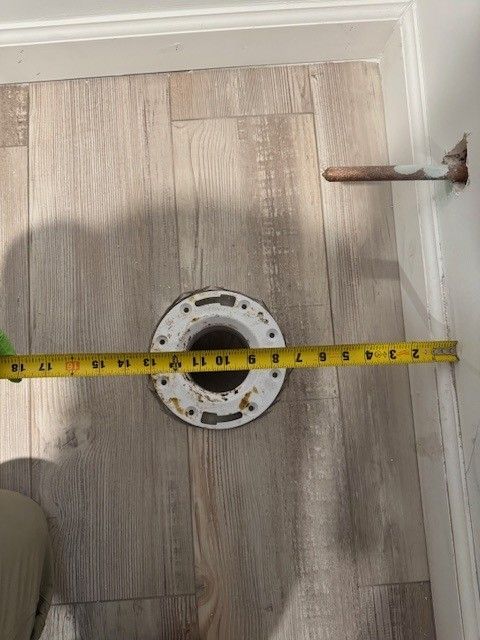Toilet flange on a light wood floor being measured by Jared Steen of Steen & Son Plumbing and Heating in Mays Landing, New Jersey