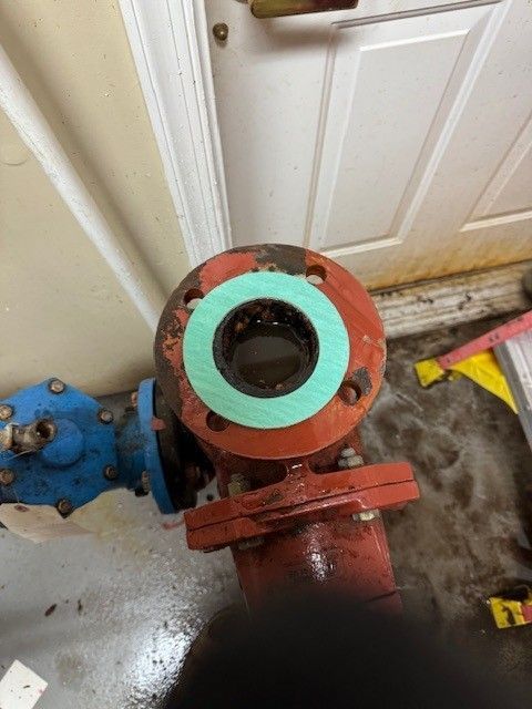 a red, 3 inch commercial water pipe with green gasket being repaired by steen & son plumbing and heating