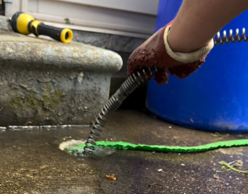 Steen & Son Plumbing and Heating technician unblocks a drain with a metal coil and a green hose