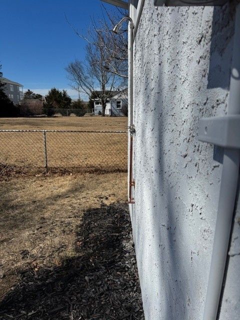 Side view of a stucco wall with an outdoor shower installed by steen & son plumbing and heating