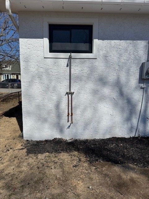 a white exterior wall of a house with window and copper pipes for an outdoor shower installed by steen & son plumbing and heating