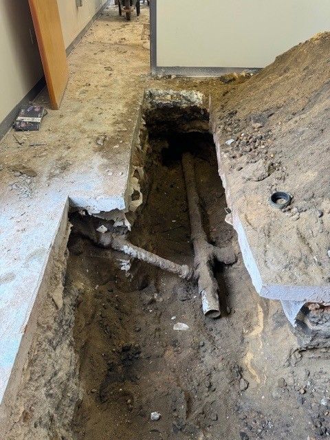 Trench dug in floor by steen & son plumbing and heating exposes plumbing pipes in a building located in mays landing, new jersey