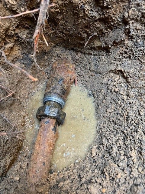 Rusty water pipe being drained in a dirt excavation by steen & son plumbing and heating