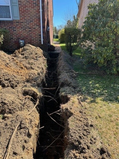 A deep trench for a new water line dug between two brick houses in mays landing, new jersey by steen & son plumbing and heating