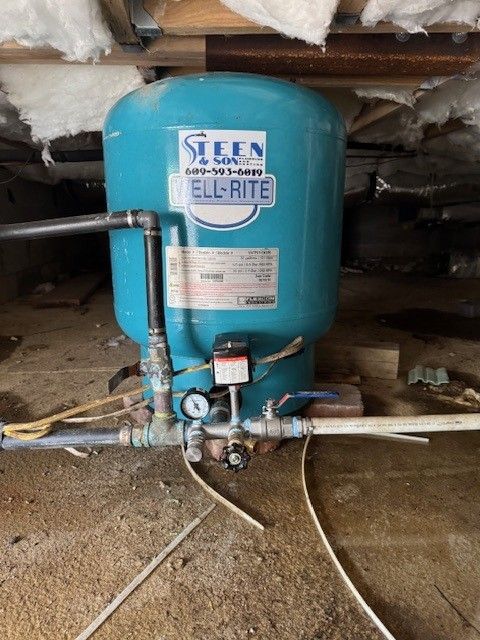 a blue well tank with a broken t assembly being installed by steen & son plumbing and heating