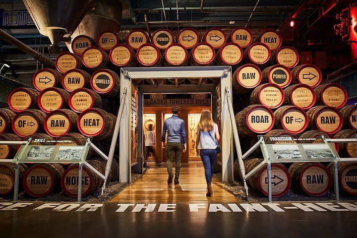 Um homem e uma mulher passam por uma porta cercada por barris.