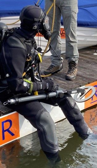 Een man in een wetsuit zit op een boot met de letter r erop