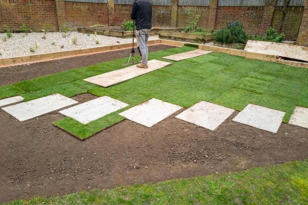 Freshly laid turf surrounds newly placed slab stepping stones in a recently landscaped garden.