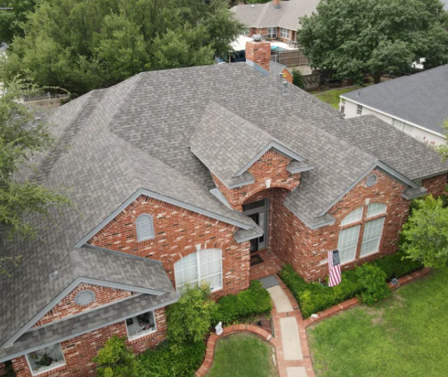 An aerial view of a brick house with a gray roof.