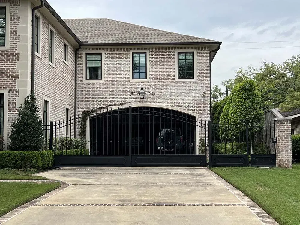 Brick house with arched garage, black gates, and driveway.