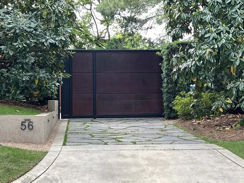 Dark brown gate set between green bushes, numbered 56, and concrete driveway.