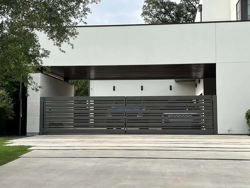 Gray horizontal slat driveway gate in front of a modern white house with a covered entry.