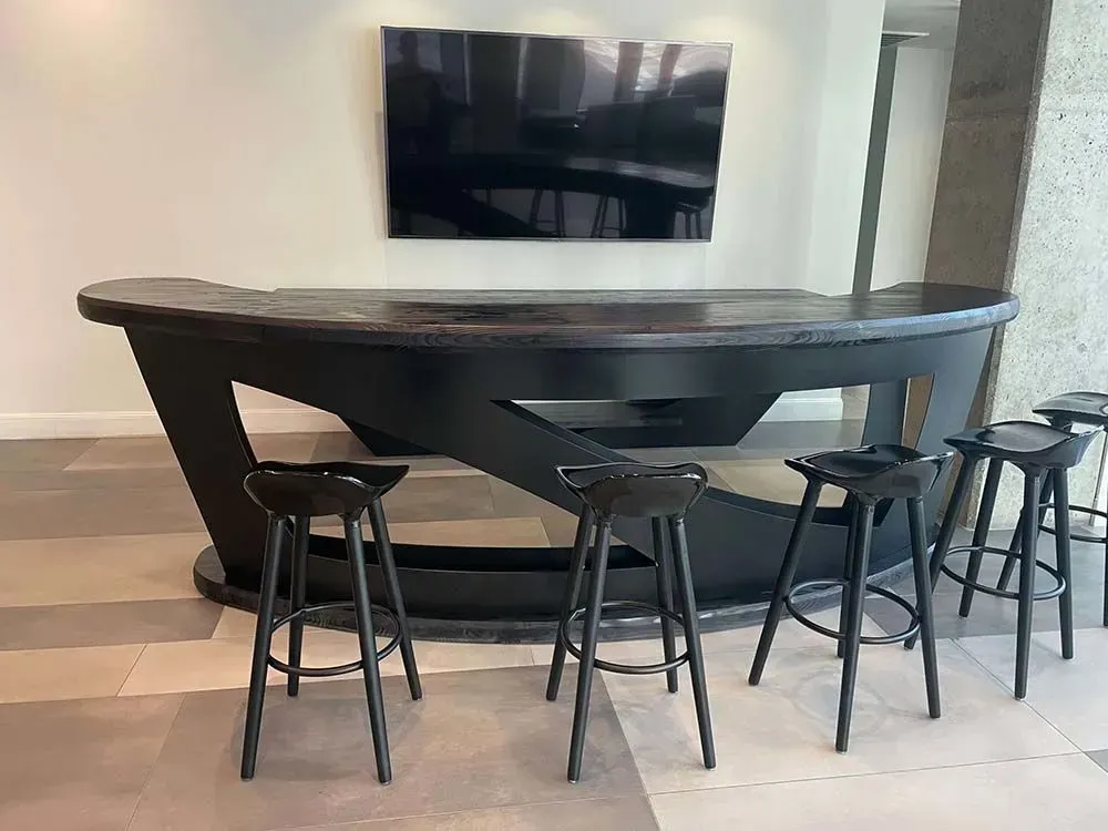 A black bar with stools in front of a TV, set against a neutral wall and floor.