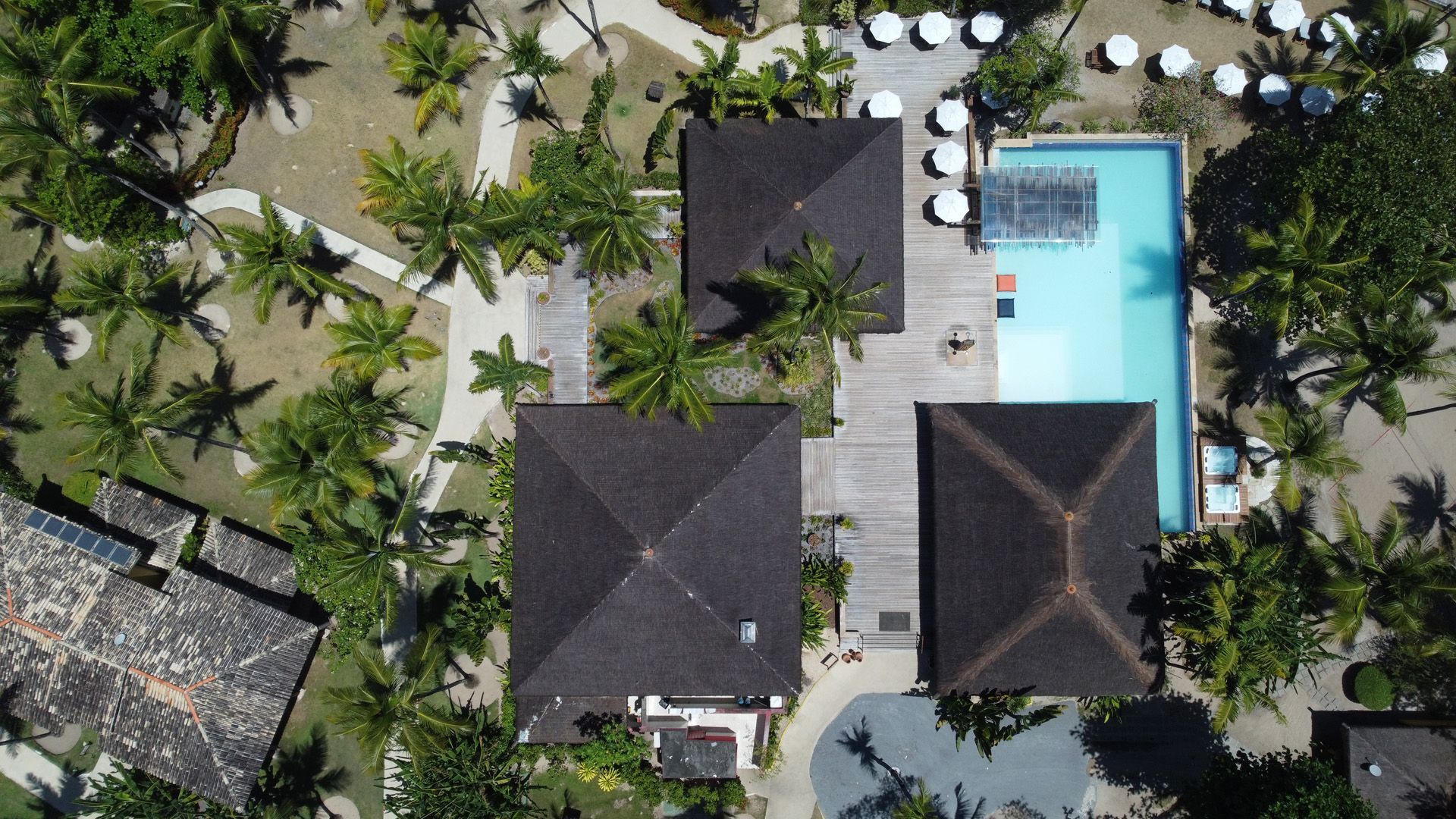 Vista aérea de edifícios com telhados marrons, uma piscina e árvores.