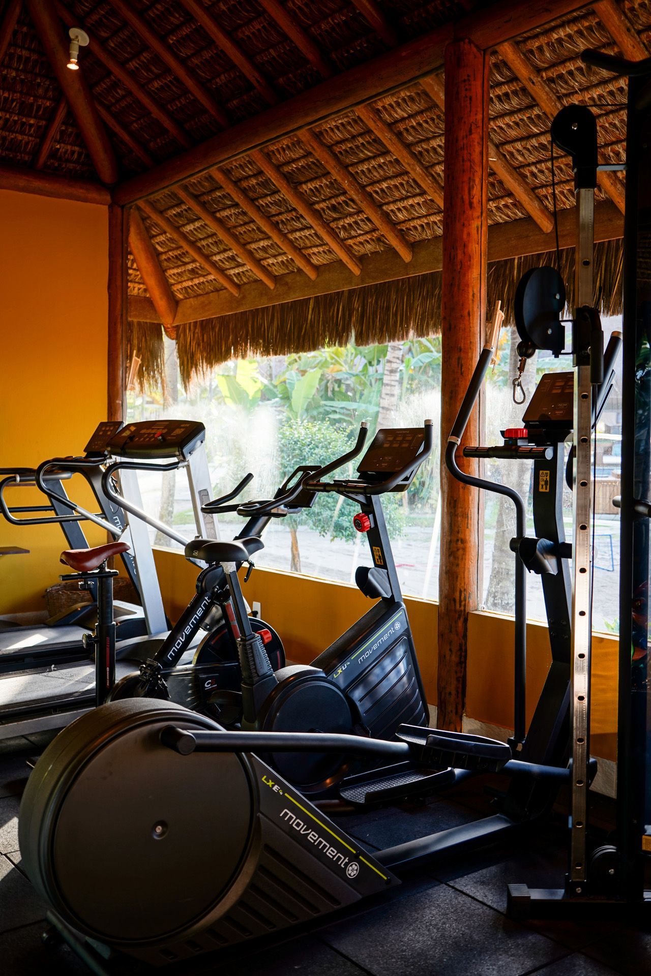 Academia com aparelhos de ginástica sob um telhado de palha.
