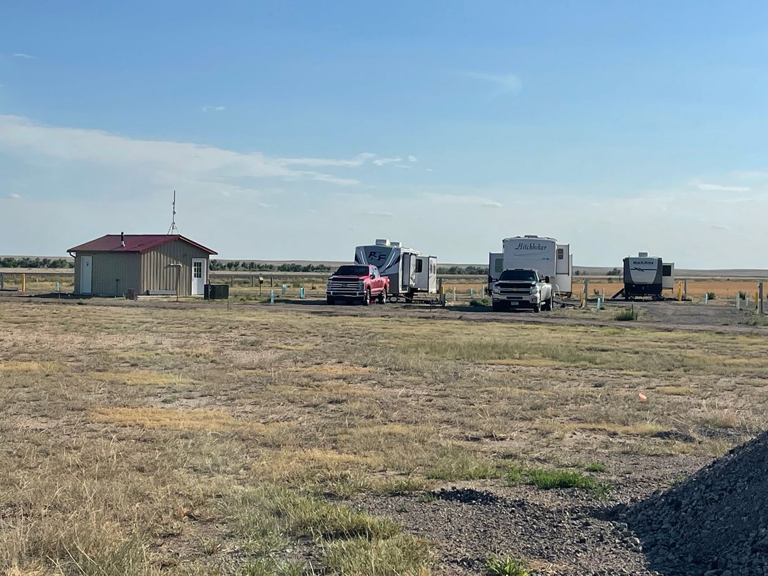 A group of rvs are parked in a field next to a building.