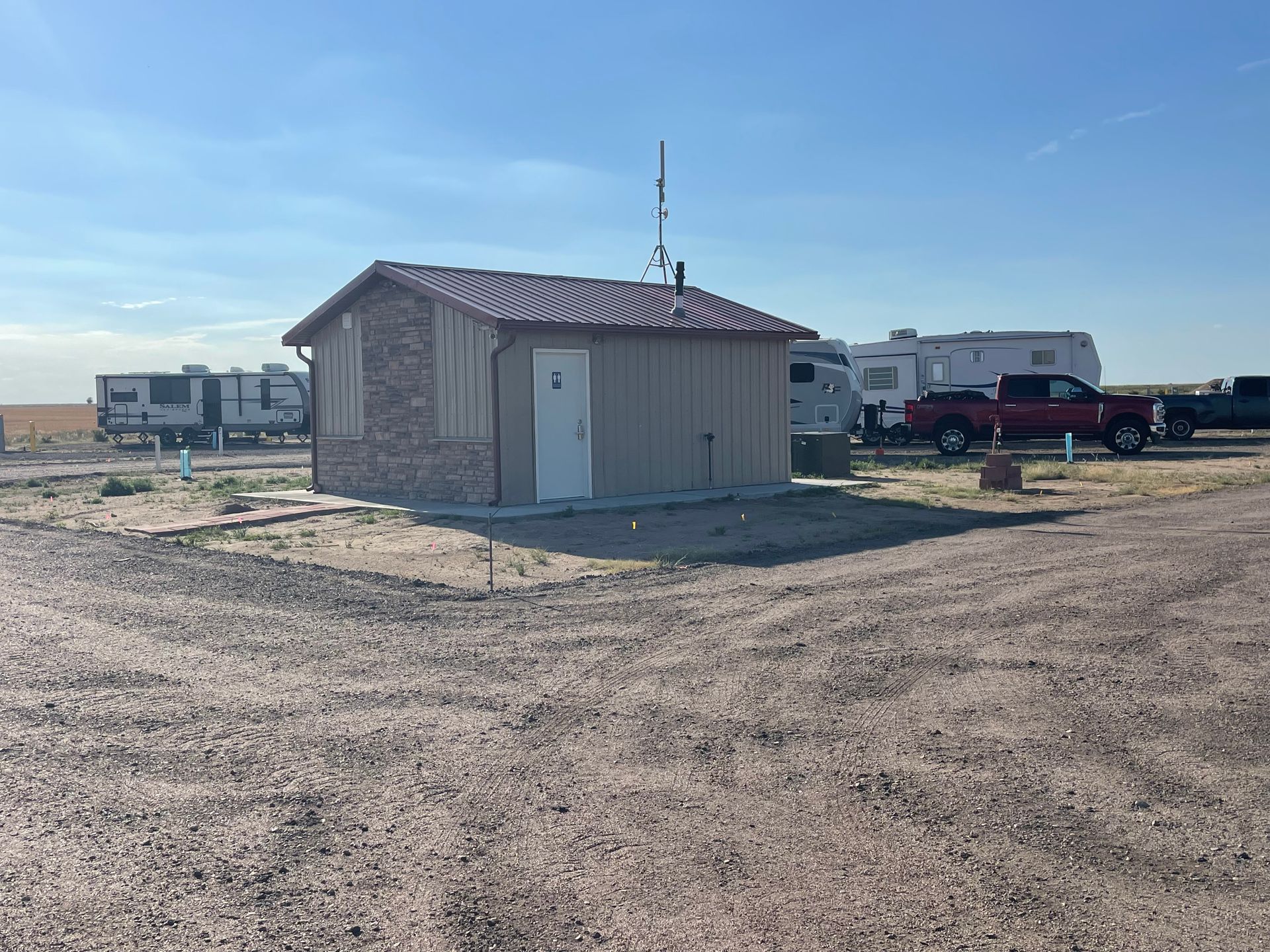 A small house is sitting in the middle of a dirt field.