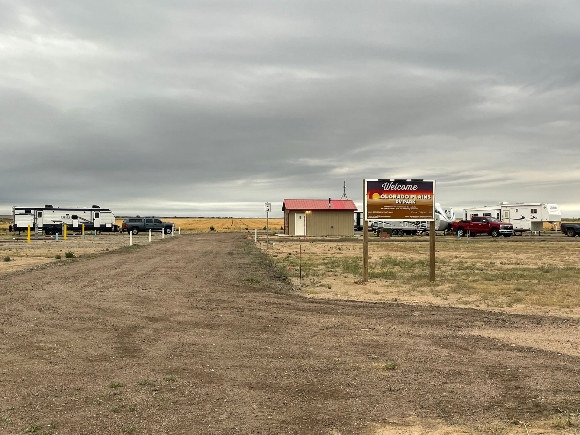 A dirt road leading to a rv park with a sign in the foreground.