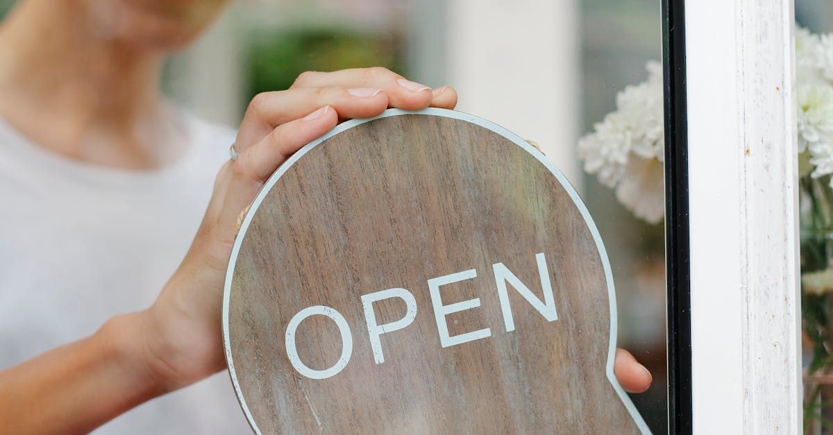 A person is putting an open sign on a glass door.