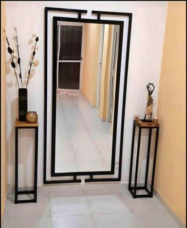 Un pasillo con un espejo de cuerpo entero y dos mesas.