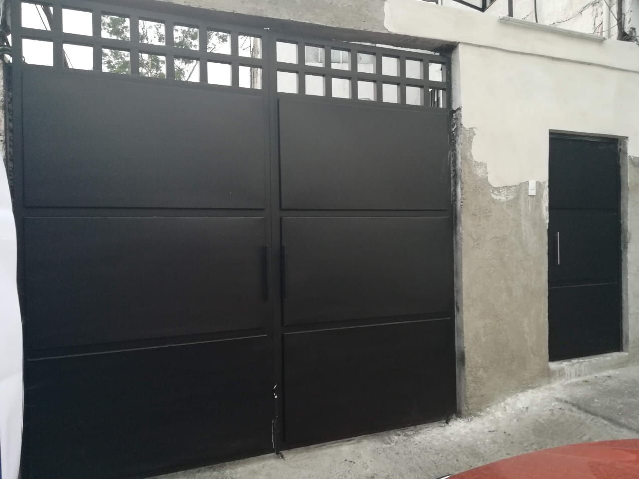 Una puerta de garaje negra está al costado de un edificio.