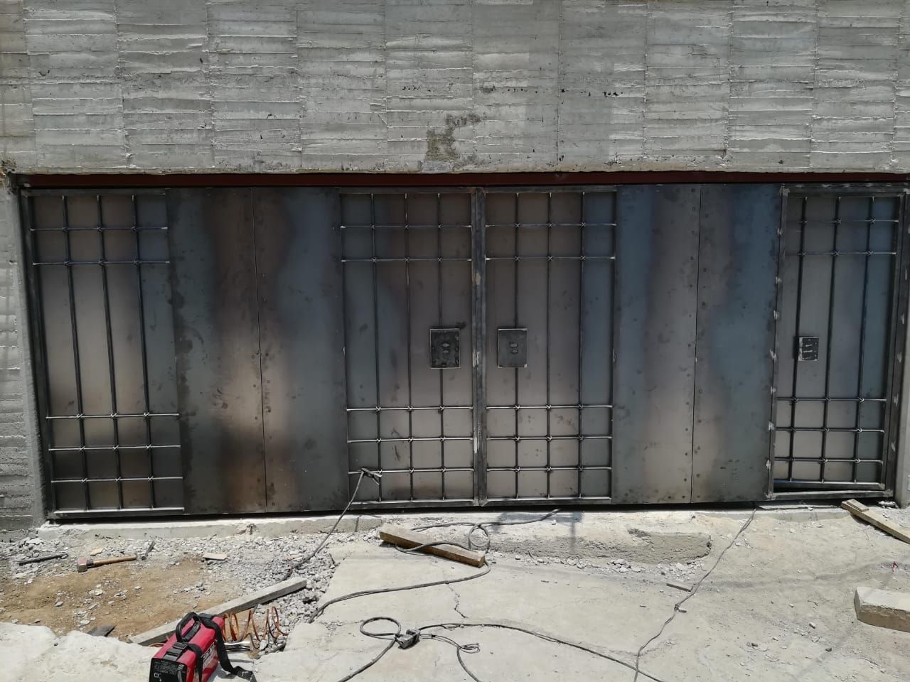 Se está construyendo una puerta de garaje de metal sobre una pared de hormigón.