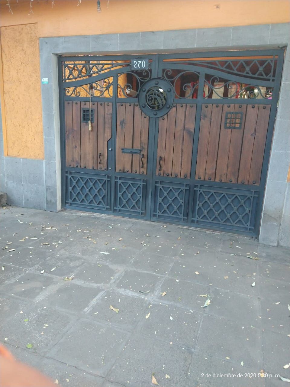 Una puerta de hierro forjado con puerta de madera se encuentra frente a un edificio.