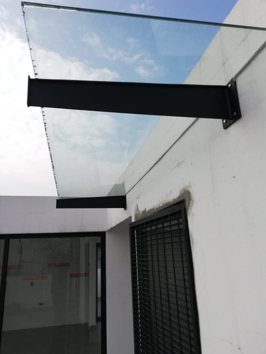 Un edificio blanco con una marquesina de vidrio sobre una ventana.