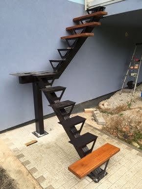 Una escalera de metal con escalones de madera se encuentra en una acera frente a un edificio.
