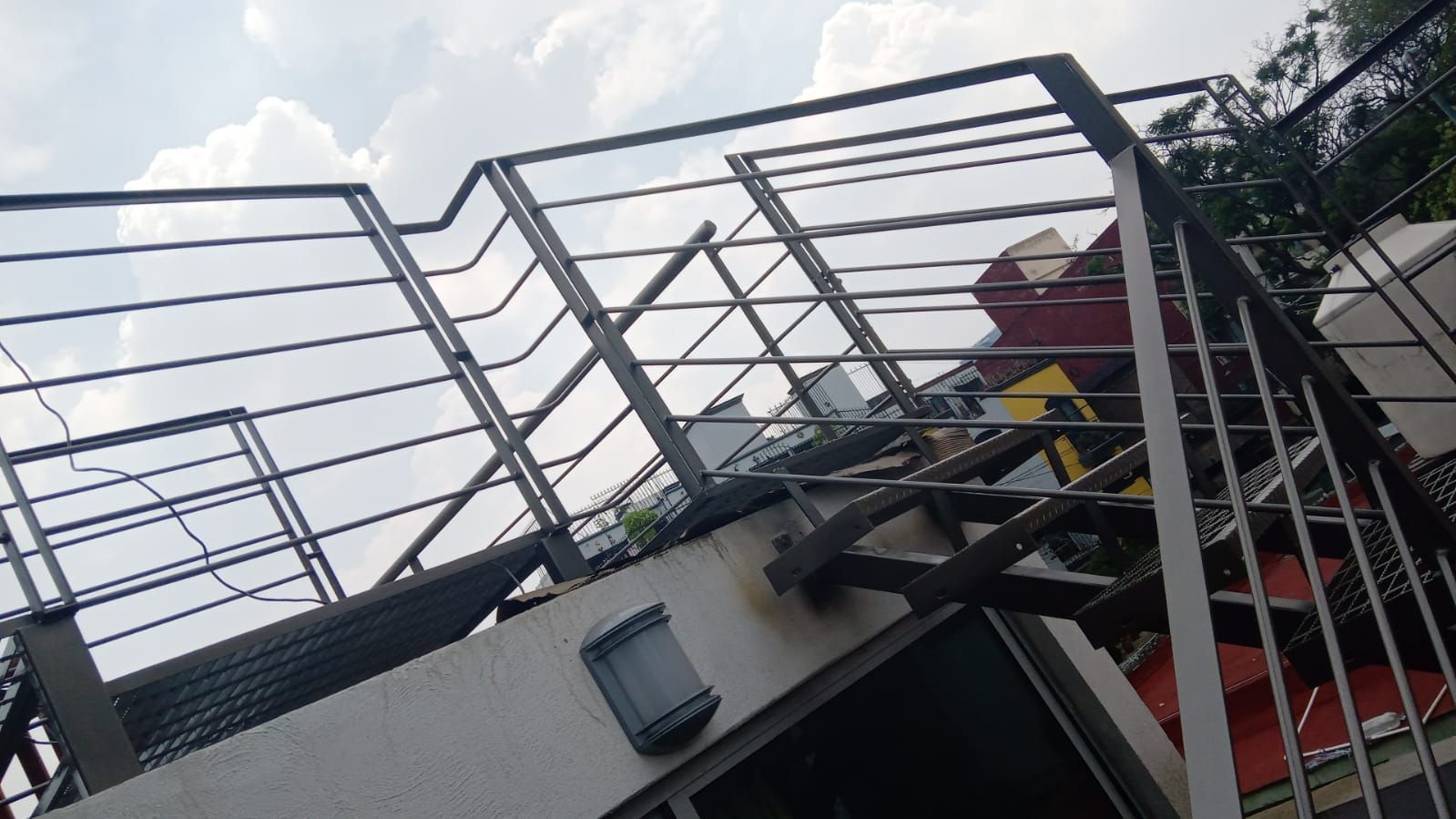 Una escalera con barandilla de metal se encuentra en la parte superior de un edificio.