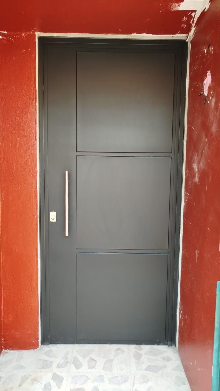 Una puerta negra está delante de una pared roja.