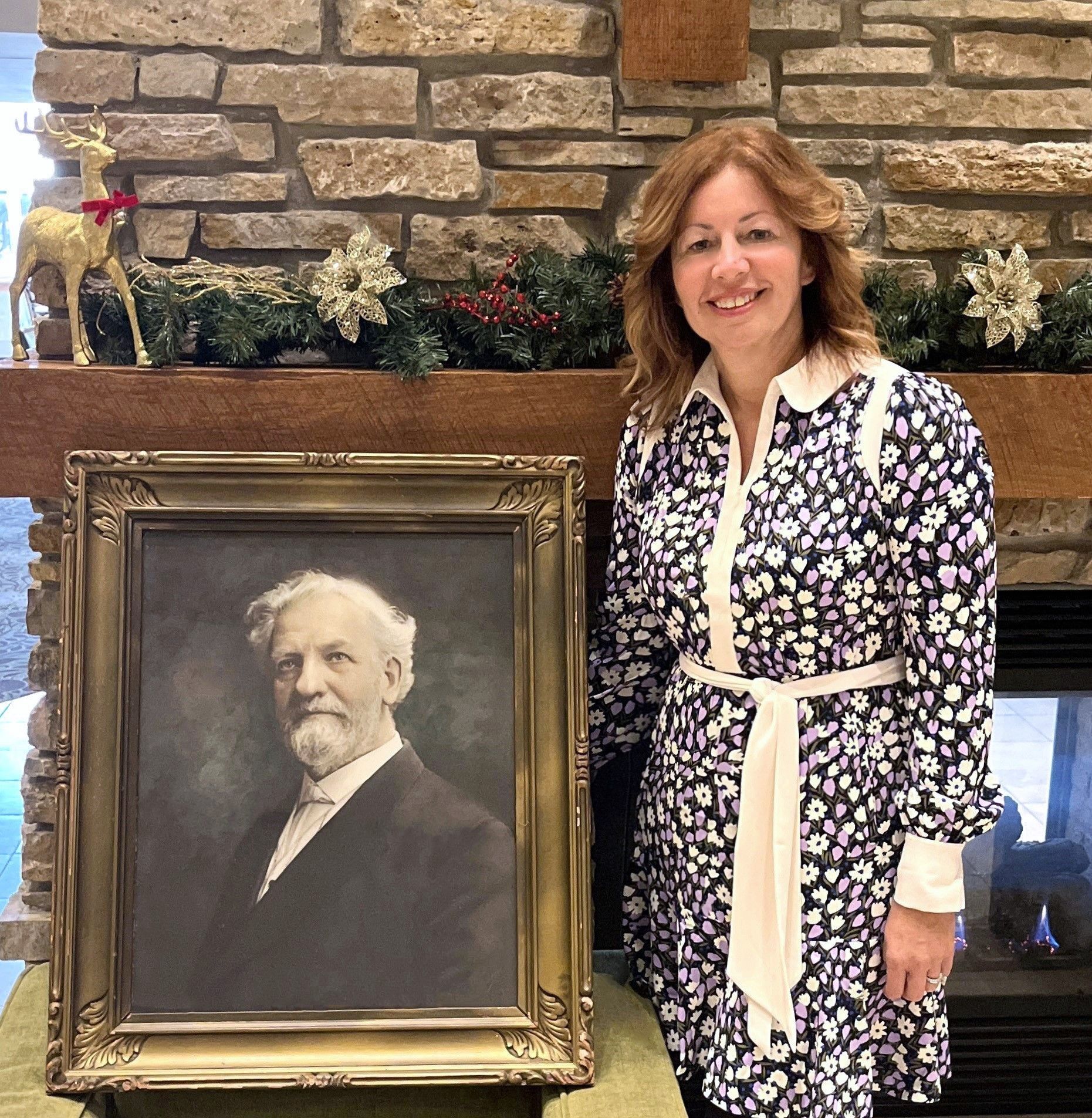 Vera poses next to the portrait of Alfred Anderson, the first chief executive of the organization.