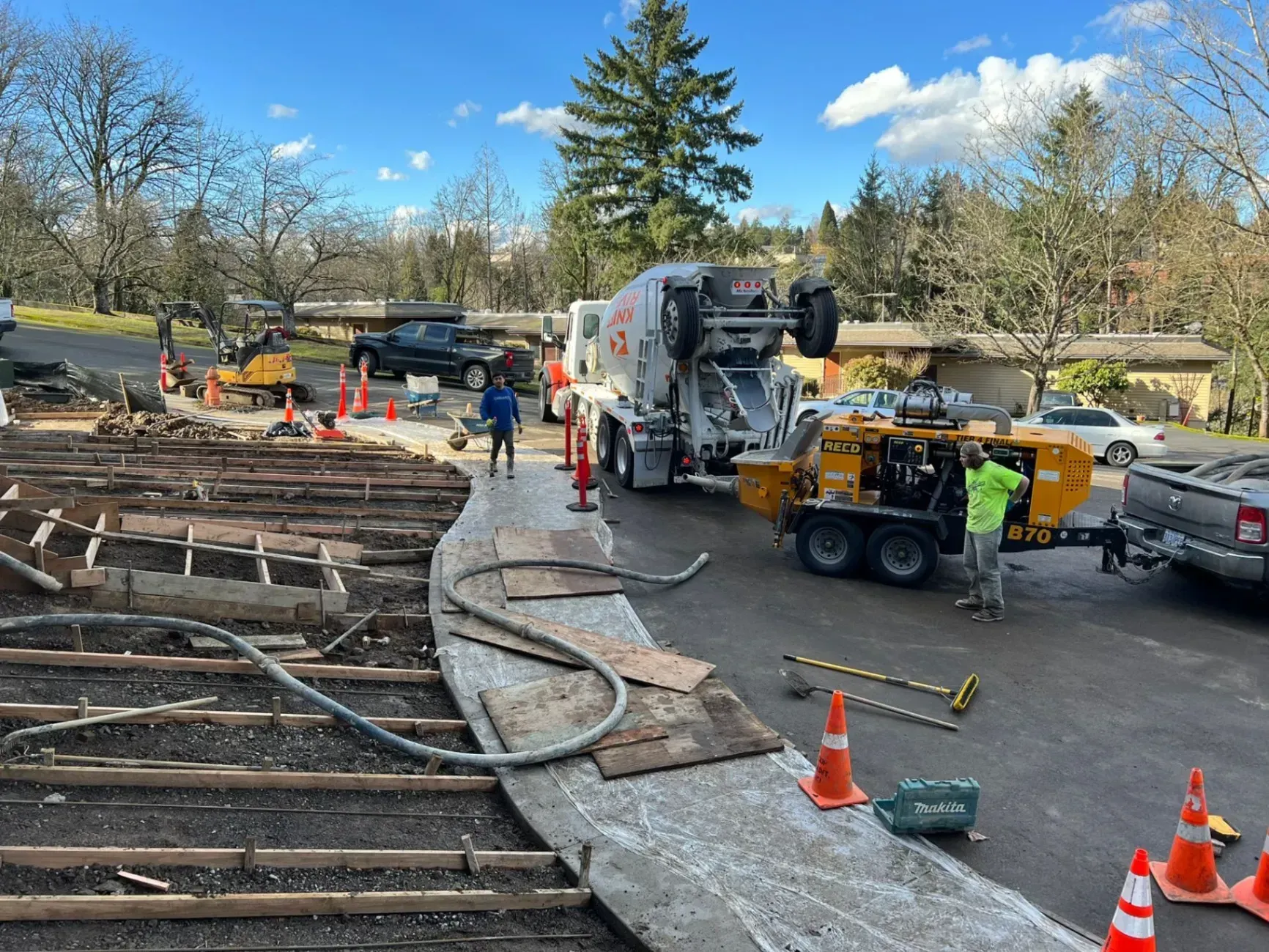 A concrete pump is being used to pump concrete into a parking lot.