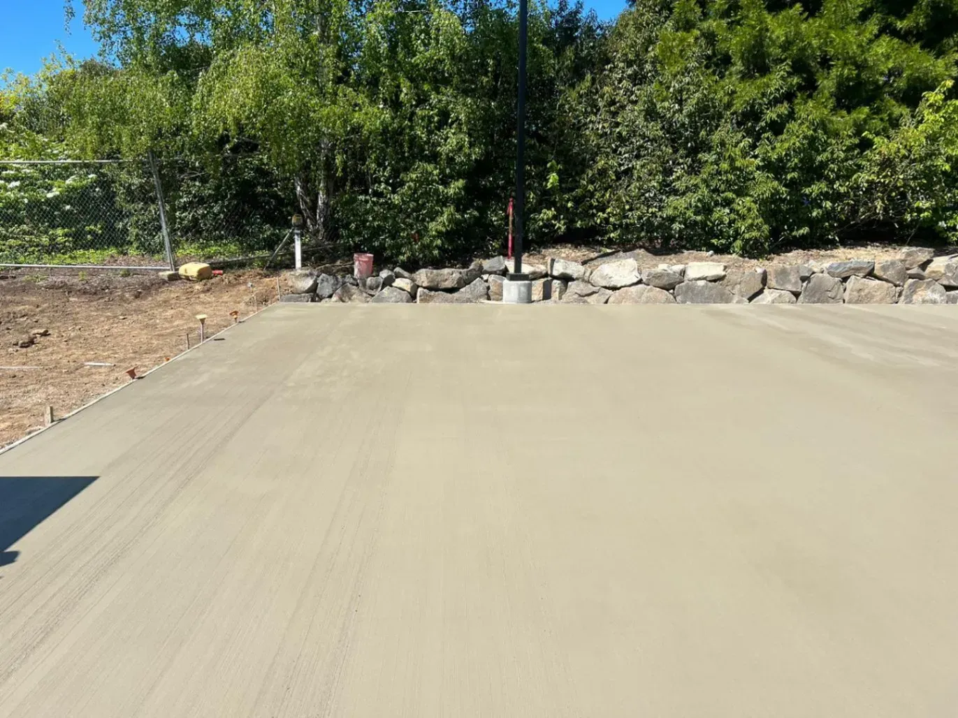 A concrete driveway is being built in a yard with trees in the background.