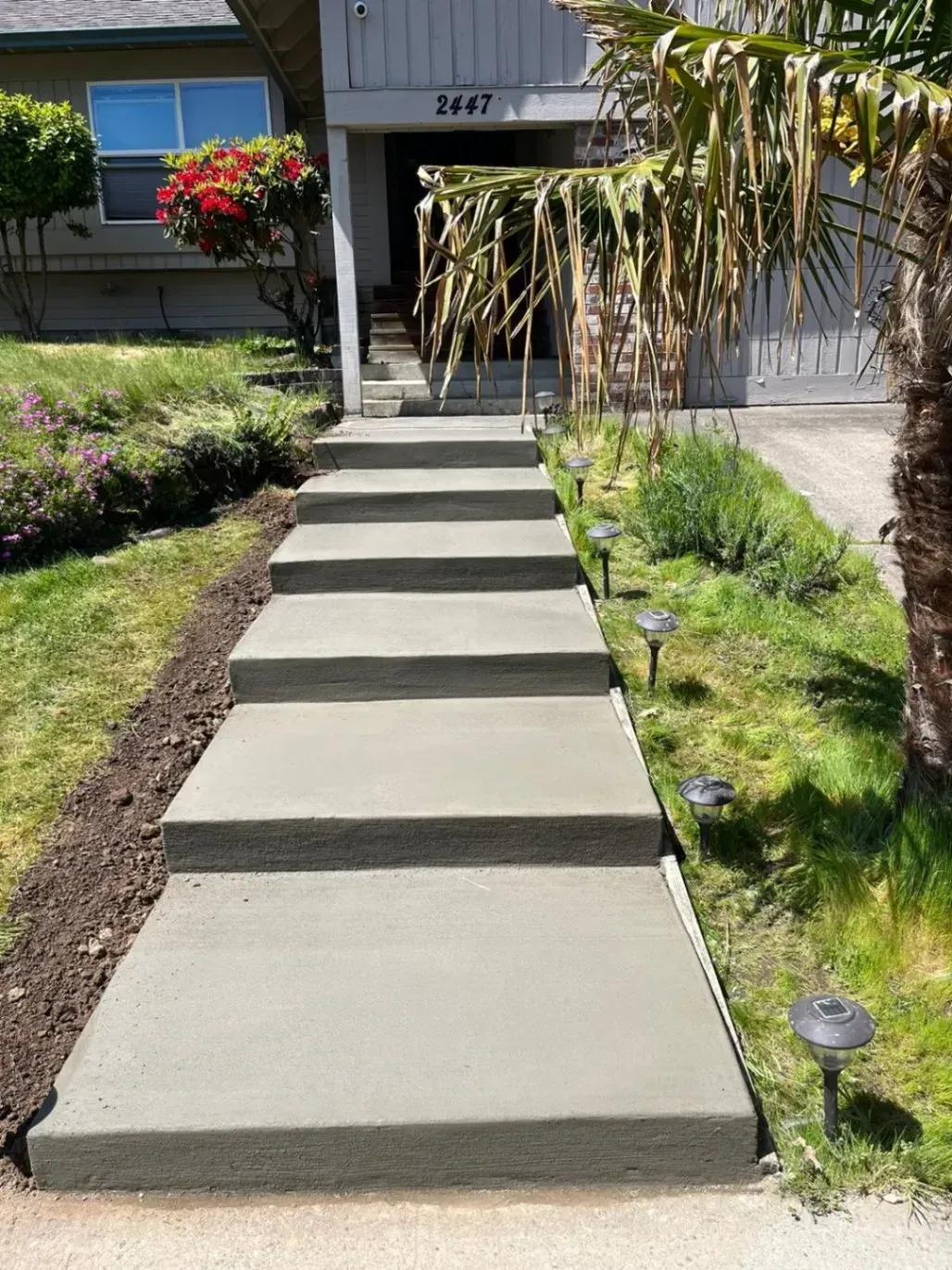A concrete walkway with steps leading up to a house.