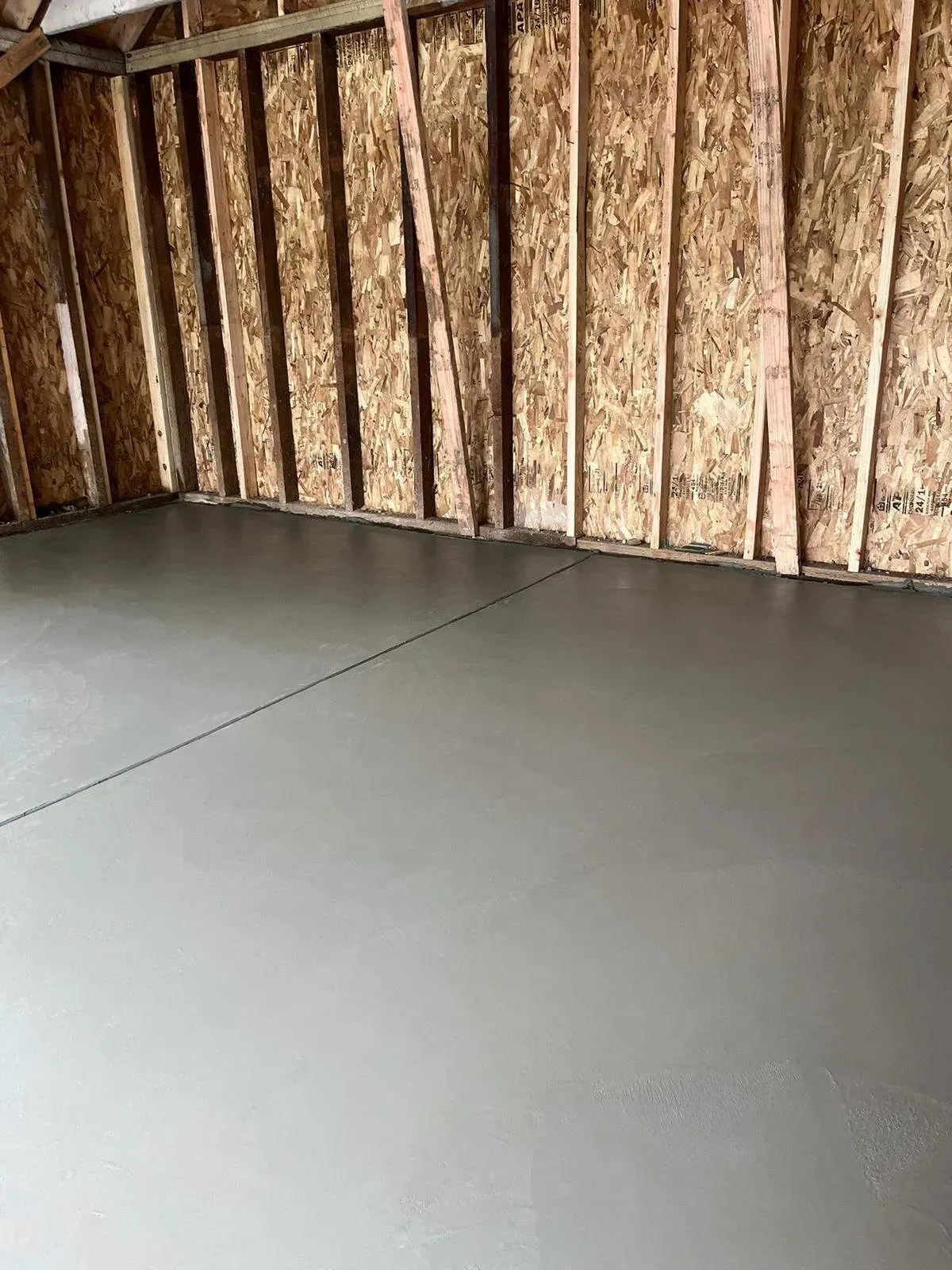 A garage with a concrete floor and wooden walls.