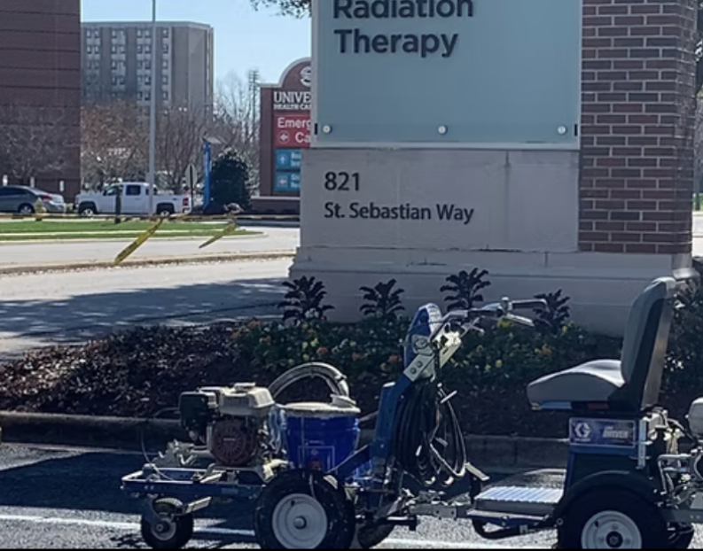 Asphalt road surface covered with dark, sealed cracks and a yellow painted lane line.