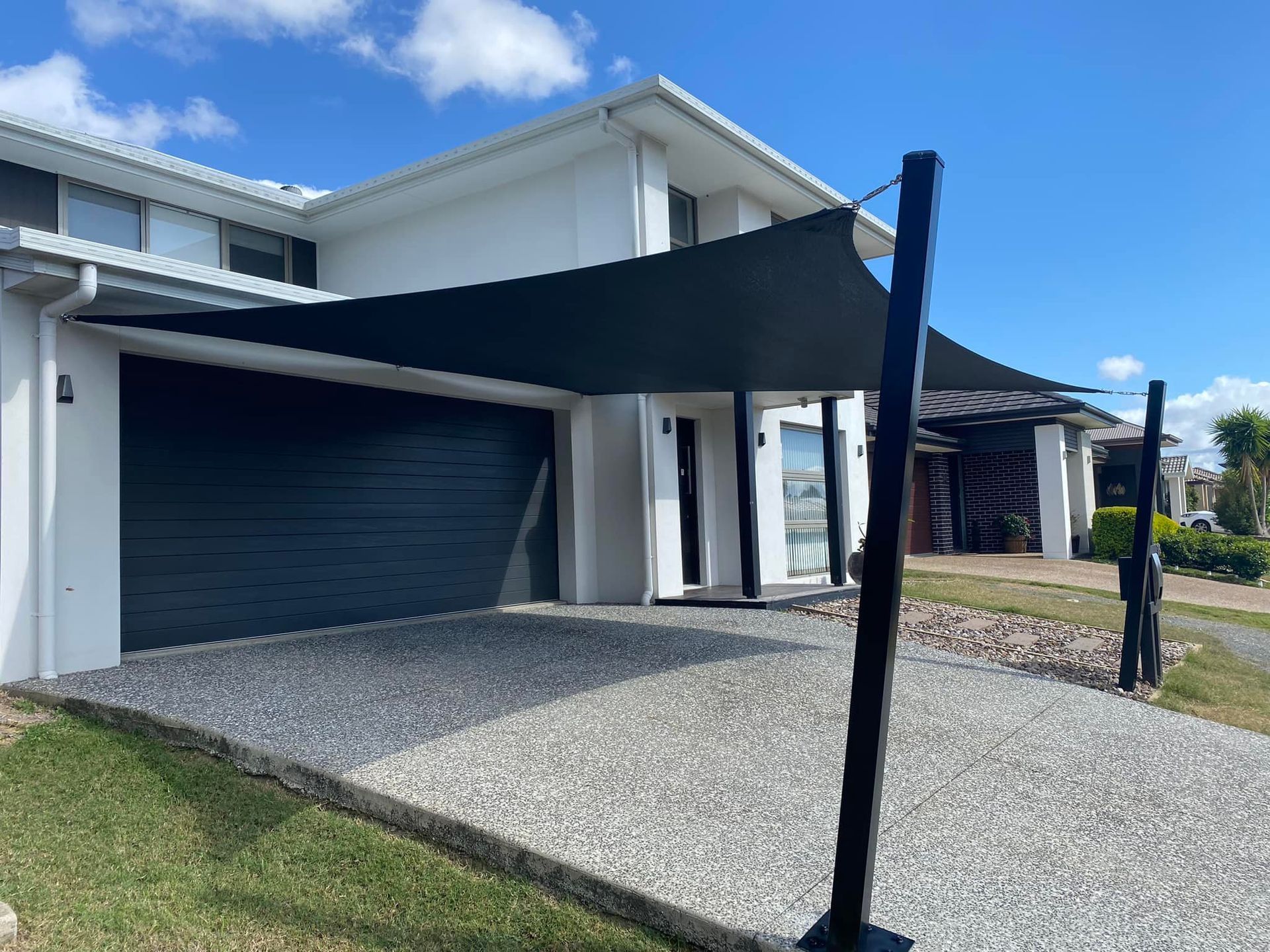 A Shade Sail Hanging Over Driveway Infront Of A Garage — Sunshine Shade & Sails In Woombye, QLD