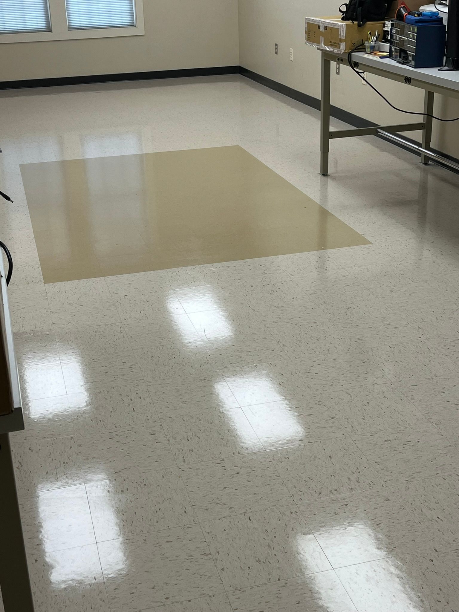 Room with shiny speckled flooring and a lighter brown rectangular patch.