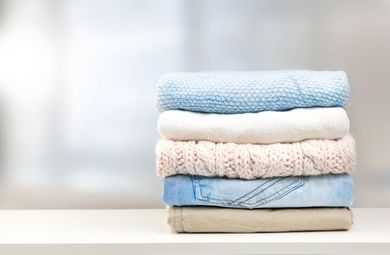 Stack of folded pastel towels on a white surface against a bright, blurred background