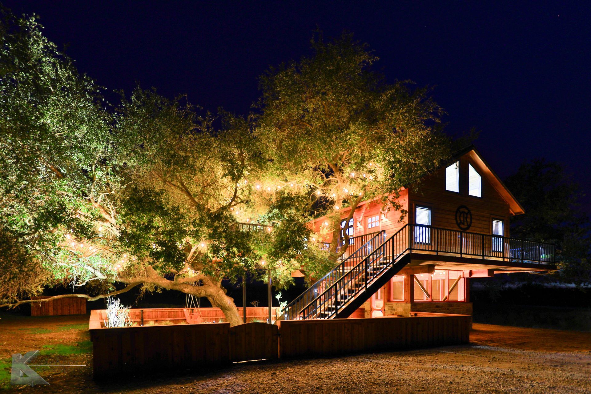 A house with stairs leading up to it is lit up at night. Magic treehouse rental airbnb