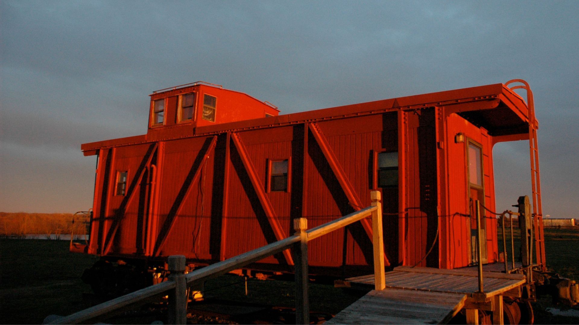 A red train car is sitting on top of a wooden platform.