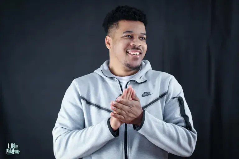 A man wearing a nike jacket is clapping his hands.
